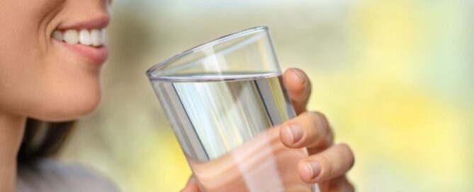 a woman smiling while drinking a glass of water