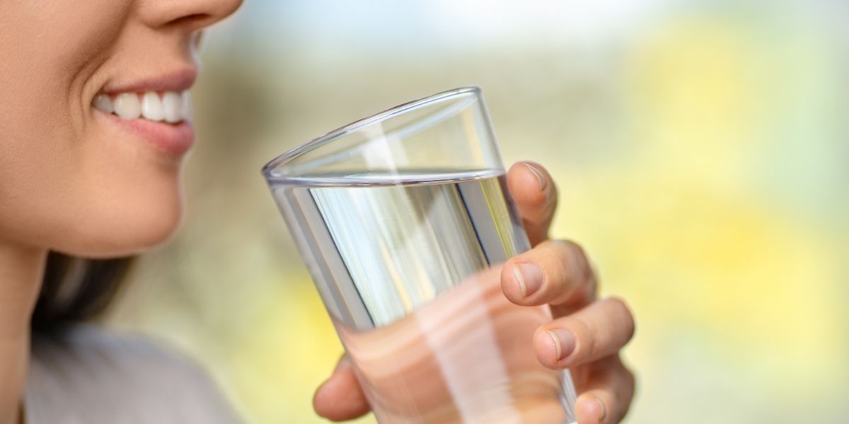 a woman smiling while drinking a glass of water